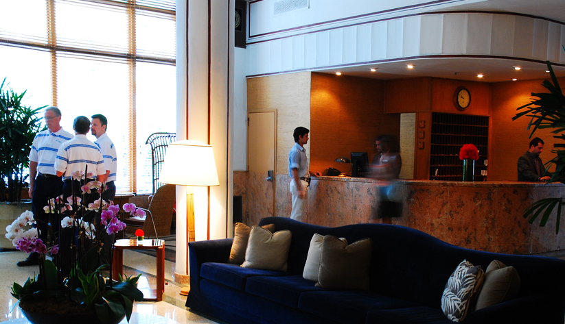 Hotel lobby-view of front desk with workers and customers.