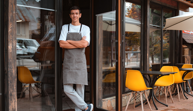 waiter standing in front of cafe in doorway with arms crossed