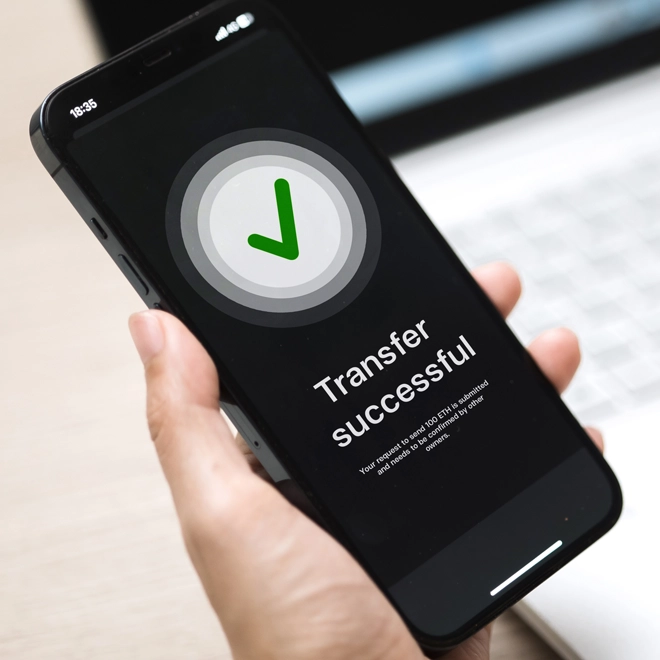 hand holding a cellphone doing a successful mobile transfer