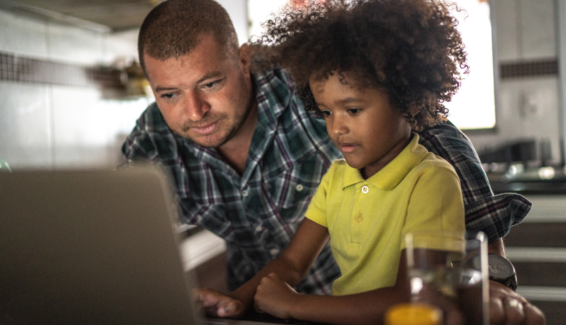 father and son looking at a open laptop together