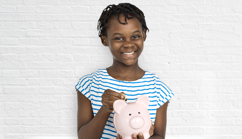 girl putting coin in piggy bank