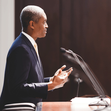 in profile, Raphael Bostic, president and CEO of the Federal Reserve bank of Atlanta, speaking at a podium as viewed from his left side
